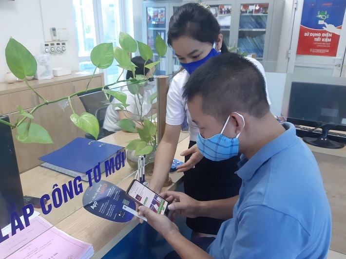 Nhân viên ngành điện đang hướng dẫn khách hàng cài đặt App EVNHANOI