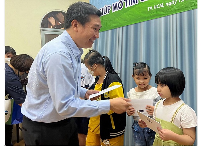 Bé Kỳ Duyên (bìa phải) nhận quà động viên từ đại diện Vinamilk