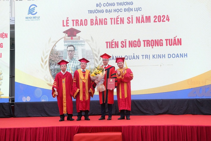 PGS.TS Vũ Đình Ngọ - Chủ tịch Hội đồng trường (thứ 2 từ trái sang) và PGS.TS Đinh Văn Châu - Quyền Hiệu trưởng trường Đại học Điện lực (bên phải) cùng đại biểu trao bằng tốt nghiệp và chúc mừng tân Tiến sĩ.