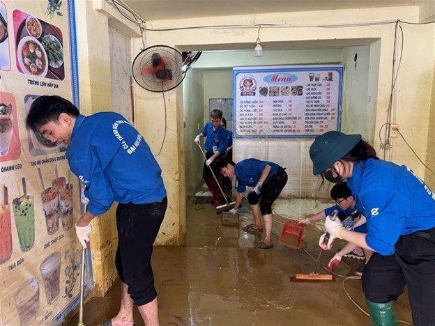 Thanh niên tình nguyện EPU dọn dẹp bùn đất sau bão lũ cho người dân.