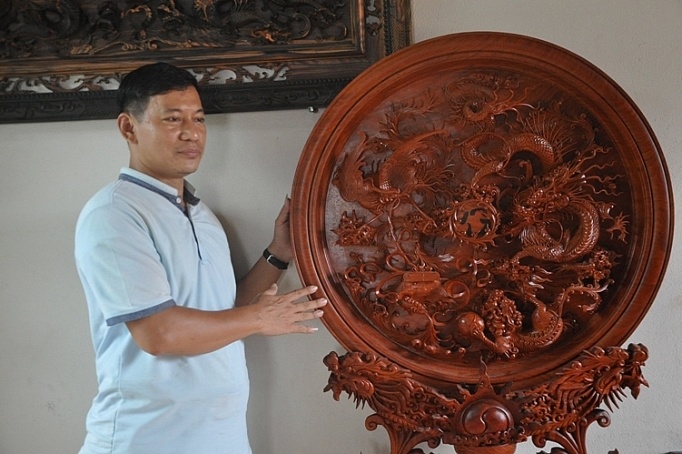 nghệ nhân Nguyễn Trần Hiệp bên tác phẩm điêu khắc gỗ